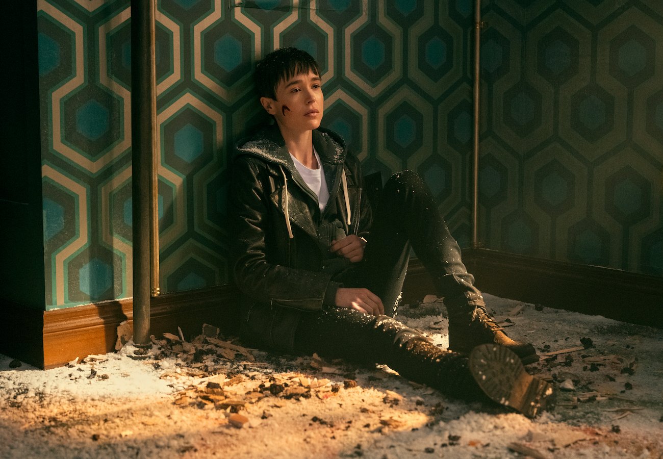 在第三季中宣布转变的维克多(埃利奥特·佩奇饰)在“雨伞学院”中靠墙而坐，脸颊流血。