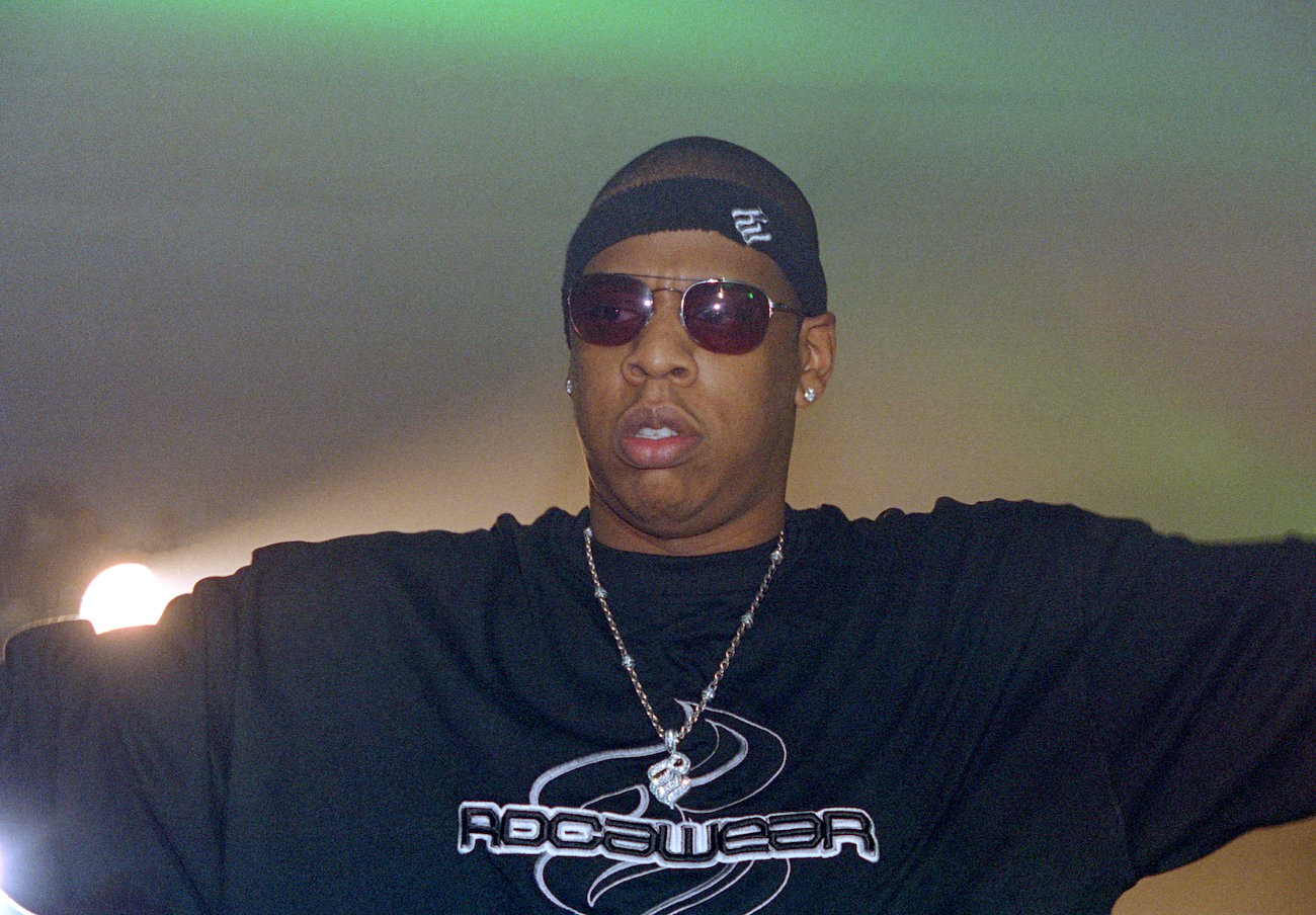 Jay-Z身穿黑色t恤，在绿色背景下与皮条客C一起在Big Pimpin后面说唱