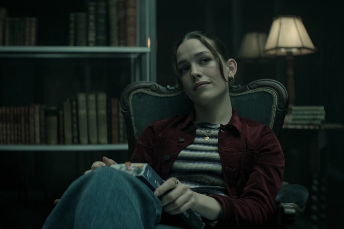 在《You》第四季第二部预告片中，洛芙·奎因穿着条纹上衣和栗色夹克坐在椅子上。