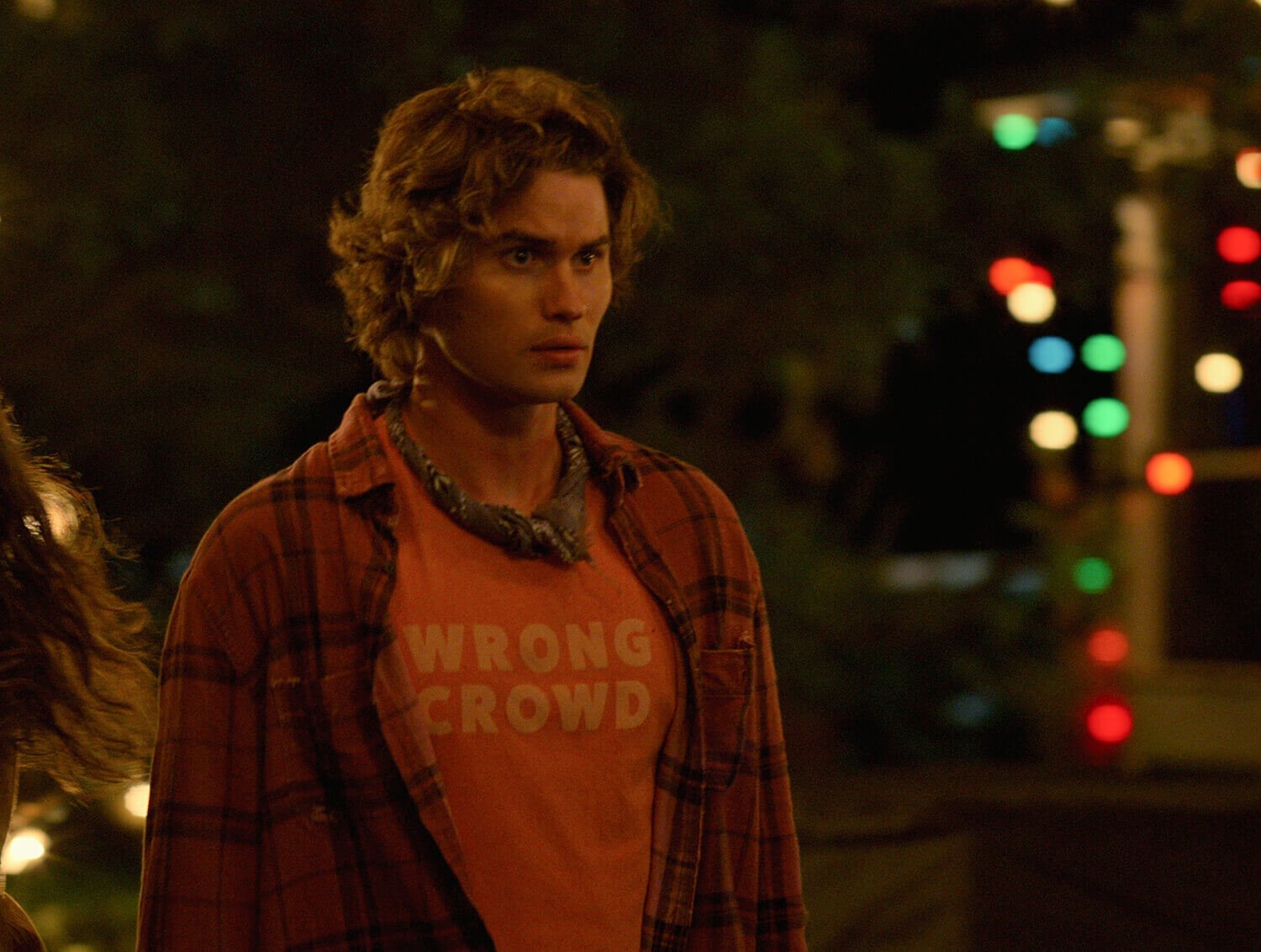 《银行外》第二季:Chase Stokes饰演John B，穿着红色法兰绒t恤，脖子上缠着裹尸布头巾