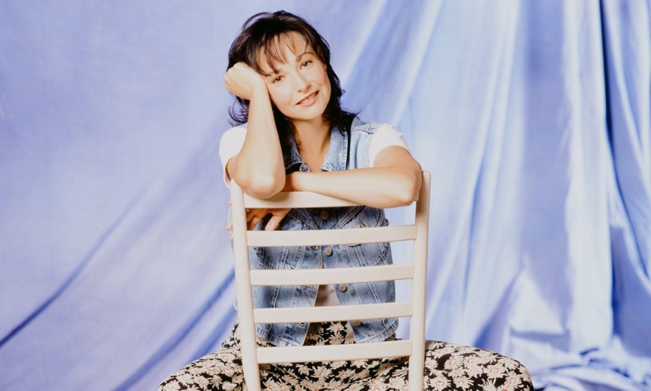 Leila Kenzle坐在一张白色椅子上，扮演Fran Devanow，为《Mad About You》拍摄宣传照。