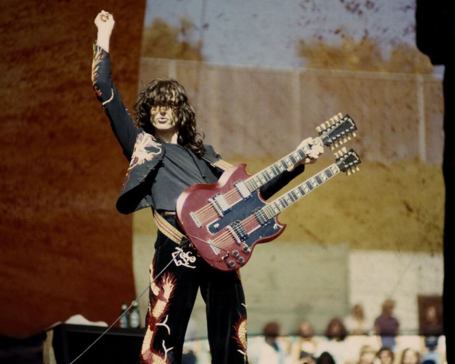 1977年，吉米·佩奇(Jimmy Page)在加州奥克兰的一场音乐会上，穿着他那套带有红龙图案的黑色西装，弹着双颈吉他。