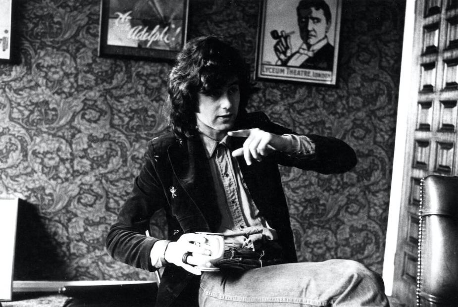 1973年，齐柏林飞艇乐队吉他手吉米·佩奇右手拿着咖啡杯，左手指着窗外。
