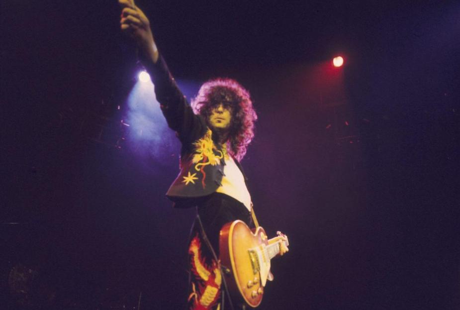 1975年齐柏林飞艇演唱会上，吉米·佩奇举起右手弹吉他。