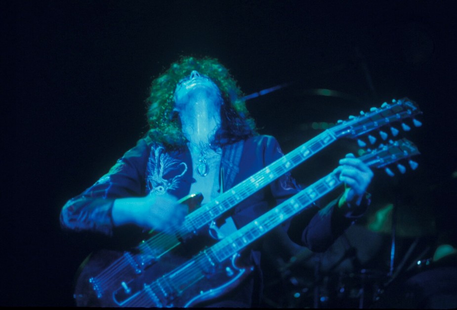 吉米·佩奇在1975年齐柏林飞艇演唱会上弹奏双颈吉他时向上看。
